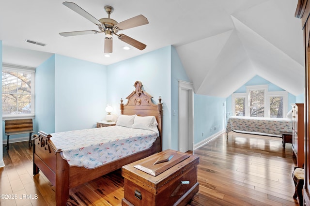 bedroom featuring lofted ceiling, multiple windows, wood finished floors, and visible vents