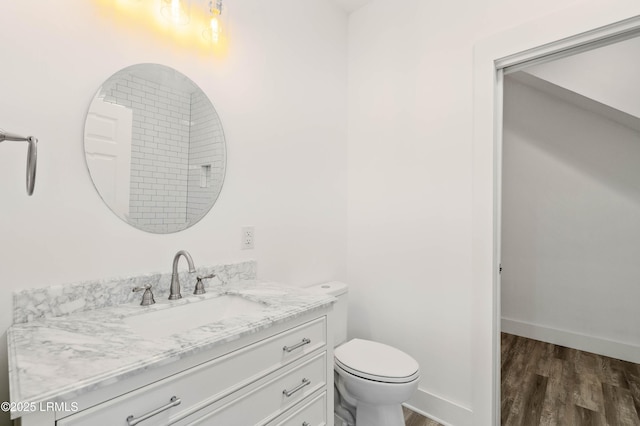 bathroom with toilet, wood finished floors, vanity, and baseboards