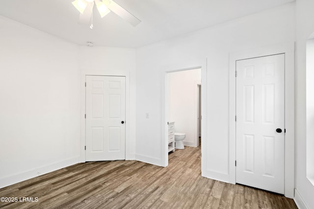 unfurnished bedroom featuring baseboards, wood finished floors, and ensuite bathroom