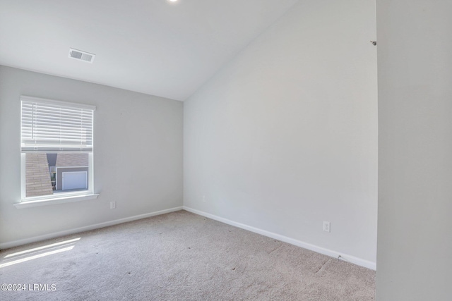 carpeted spare room featuring lofted ceiling