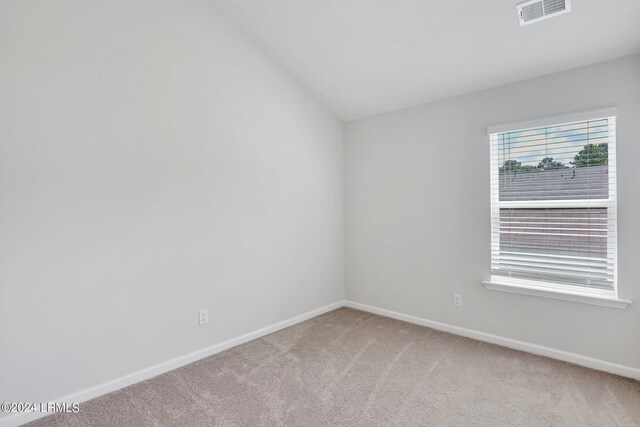 carpeted spare room with lofted ceiling