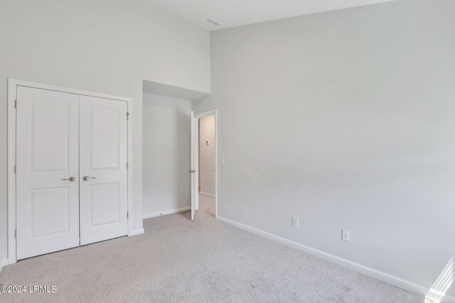 unfurnished bedroom with light carpet and a closet