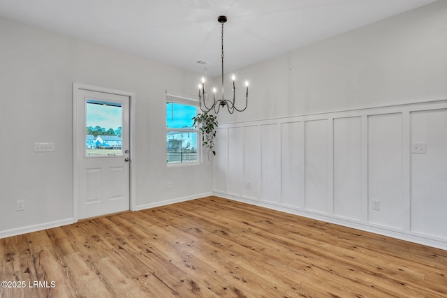 unfurnished dining area featuring a chandelier and light wood-type flooring