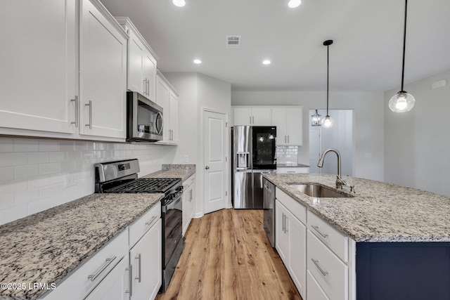 kitchen featuring sink, appliances with stainless steel finishes, decorative backsplash, white cabinets, and decorative light fixtures