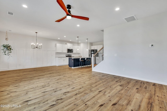 living room with ceiling fan with notable chandelier and light wood-type flooring