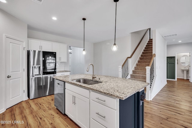 kitchen featuring pendant lighting, white cabinetry, an island with sink, sink, and stainless steel appliances