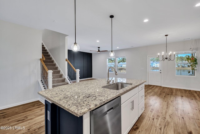 kitchen featuring sink, light stone counters, a center island with sink, stainless steel dishwasher, and pendant lighting