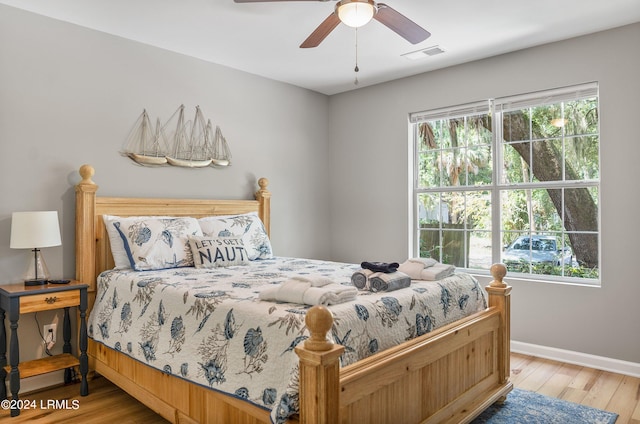 bedroom featuring visible vents, baseboards, ceiling fan, and wood finished floors