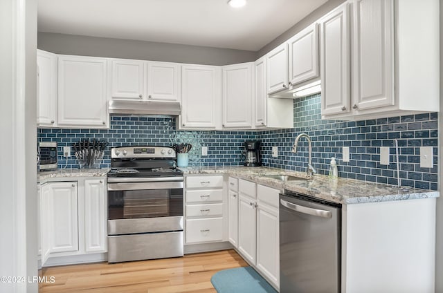 kitchen featuring under cabinet range hood, stainless steel appliances, white cabinets, and a sink