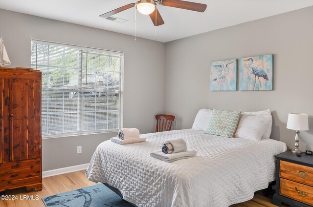 bedroom with baseboards, a ceiling fan, wood finished floors, and visible vents