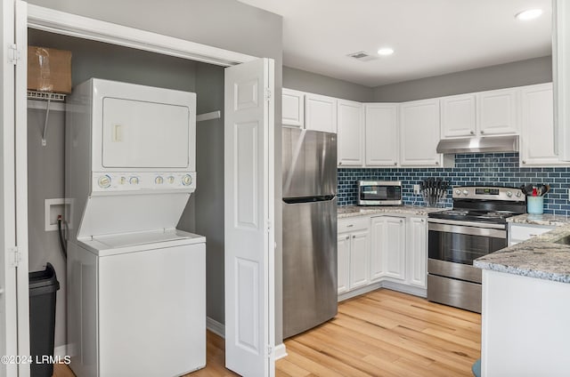 kitchen with stacked washer / dryer, visible vents, appliances with stainless steel finishes, white cabinets, and under cabinet range hood