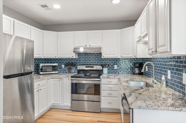 kitchen featuring visible vents, appliances with stainless steel finishes, a sink, white cabinets, and under cabinet range hood