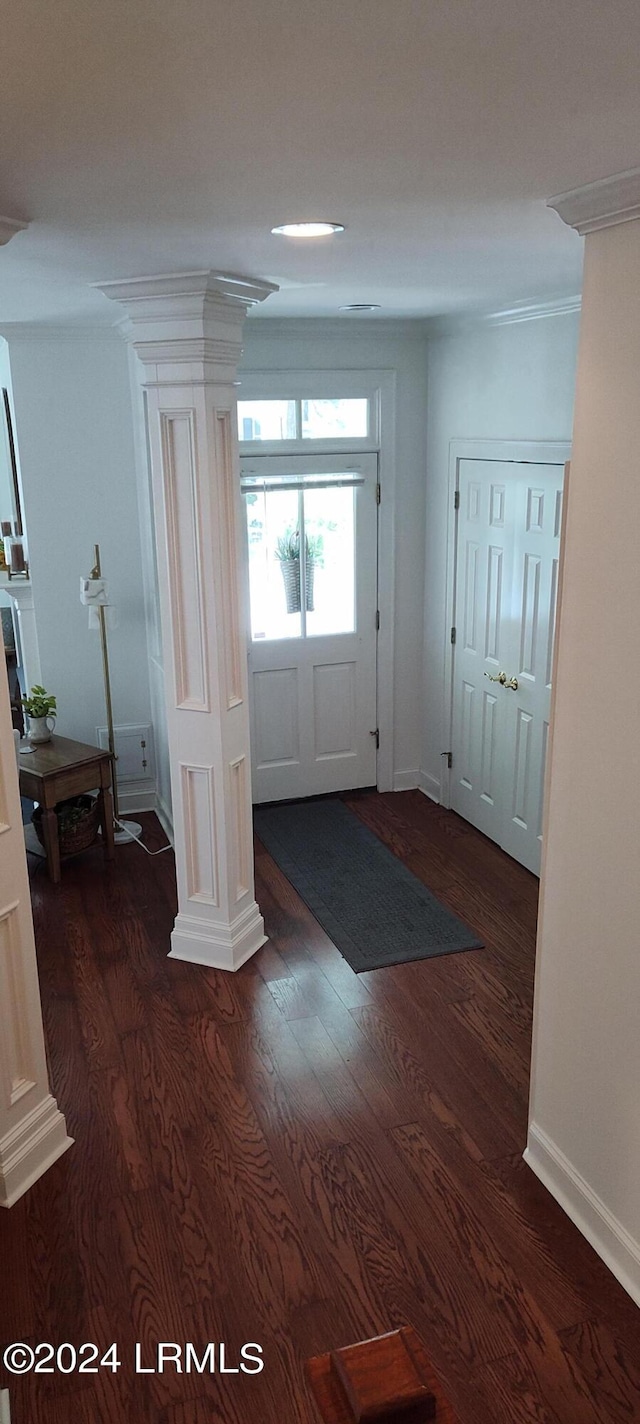 doorway with crown molding, dark hardwood / wood-style floors, and ornate columns