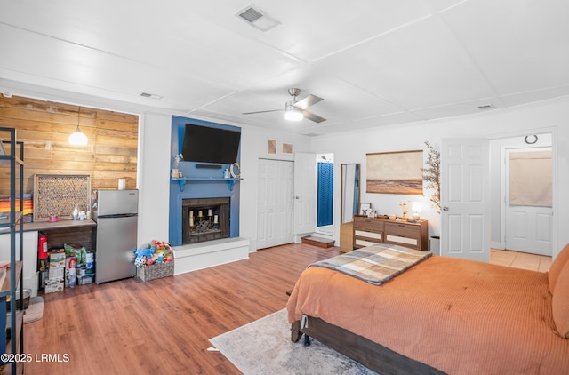 1508 London Ave, Port Royal, SC 29935 - bedroom with freestanding refrigerator, a fireplace with raised hearth, wood finished floors, and a ceiling fan