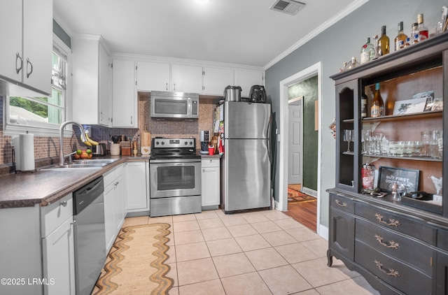 1508 London Ave, Port Royal, SC 29935 - kitchen with stainless steel appliances, white cabinets, backsplash, dark countertops, and ornamental molding