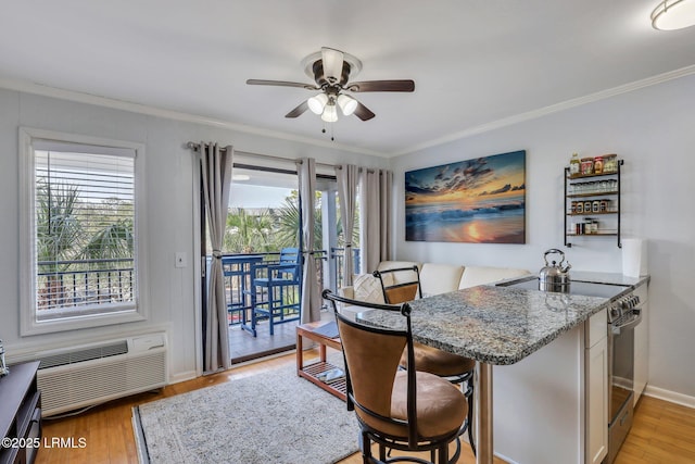 dining space with baseboards, a ceiling fan, a wall unit AC, light wood-style flooring, and ornamental molding