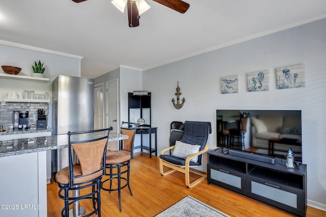 kitchen featuring stone counters, light wood-style flooring, a ceiling fan, and crown molding