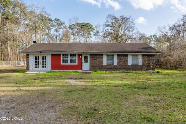 ranch-style house featuring brick siding, fence, a front lawn, and french doors