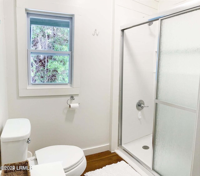 bathroom featuring toilet, a stall shower, wood finished floors, and baseboards