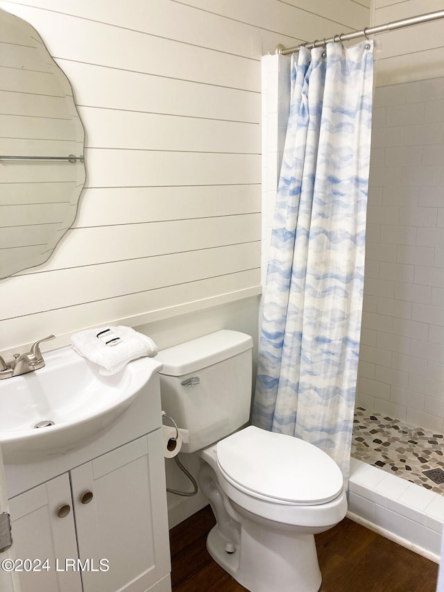 bathroom featuring wood finished floors, a shower stall, vanity, and toilet