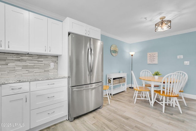 kitchen featuring backsplash, stainless steel fridge, ornamental molding, and white cabinets