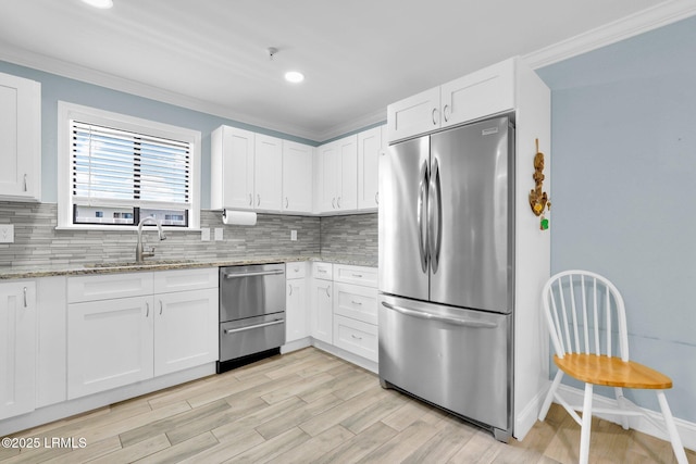 kitchen with white cabinetry, stainless steel appliances, sink, and light stone counters