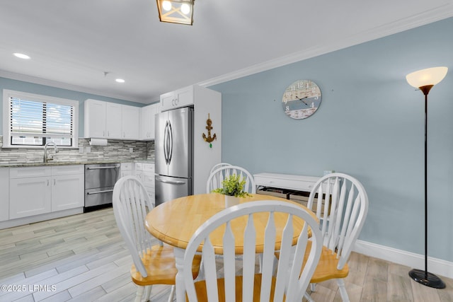 dining area with ornamental molding, sink, and light hardwood / wood-style floors