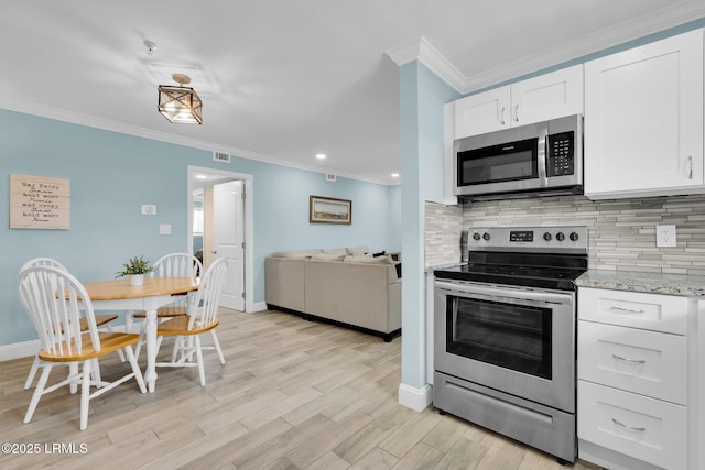 kitchen with white cabinetry, stainless steel appliances, light stone countertops, and backsplash