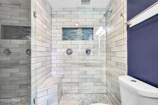 bathroom with a tile shower and toilet