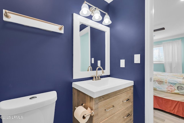 bathroom featuring vanity, crown molding, toilet, and hardwood / wood-style flooring