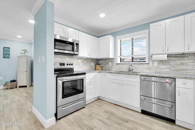 kitchen with sink, white cabinetry, appliances with stainless steel finishes, light stone countertops, and decorative backsplash