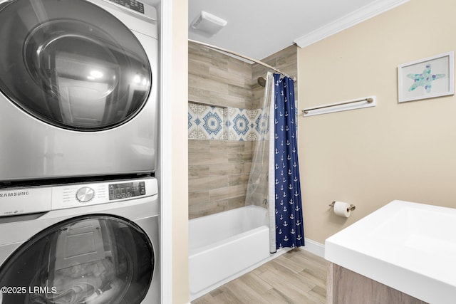 washroom featuring crown molding and stacked washer / dryer