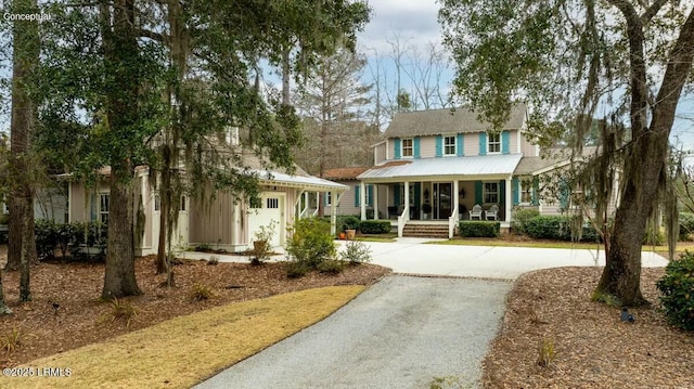 view of front of property featuring covered porch, driveway, and metal roof