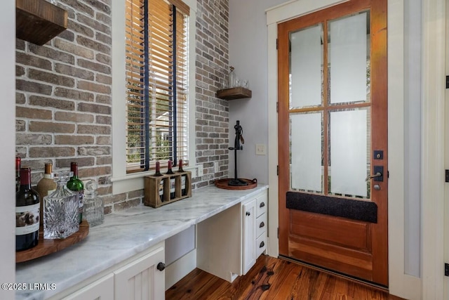 wine area with dark wood-type flooring and brick wall