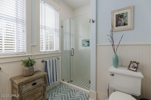 full bath featuring a wainscoted wall, a shower stall, and toilet