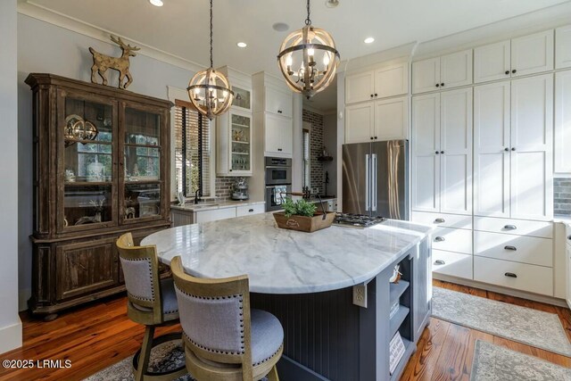 kitchen with white cabinets, stainless steel appliances, dark wood-type flooring, and decorative light fixtures