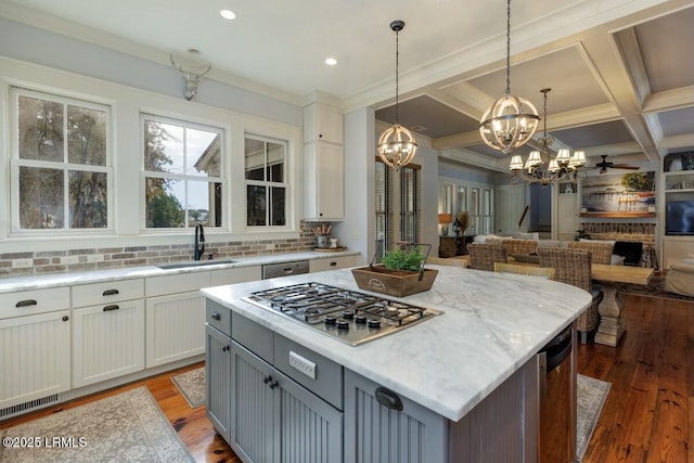 kitchen featuring light wood-style flooring, appliances with stainless steel finishes, open floor plan, a sink, and coffered ceiling