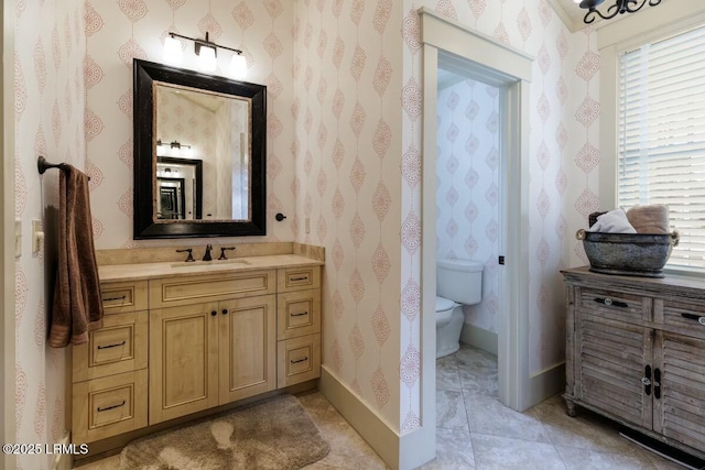 bathroom featuring vanity, toilet, and wallpapered walls