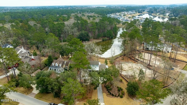 birds eye view of property featuring a water view and a wooded view