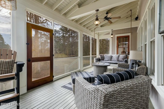 sunroom featuring lofted ceiling with beams, ceiling fan, and a wealth of natural light