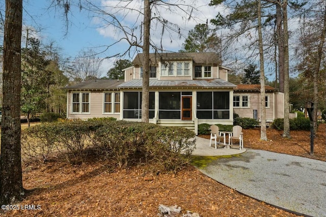 rear view of property with a sunroom, metal roof, and a standing seam roof