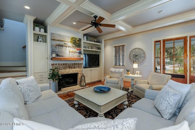 living area with beamed ceiling, coffered ceiling, wood finished floors, and a brick fireplace