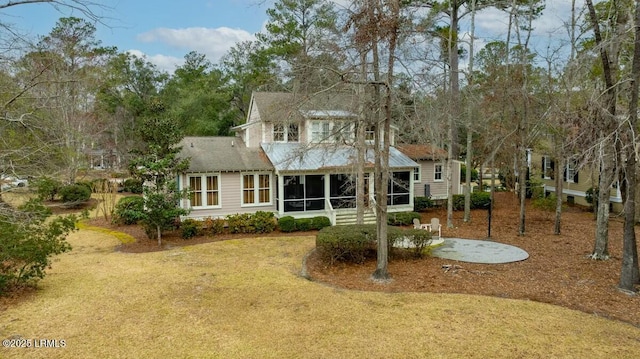 back of property featuring a sunroom and a lawn