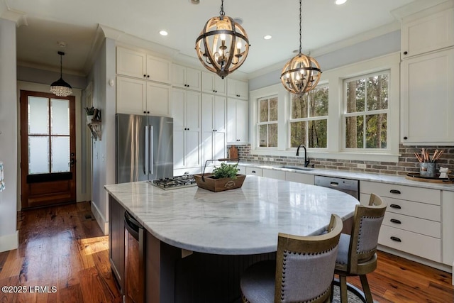 kitchen featuring crown molding, stainless steel appliances, backsplash, an inviting chandelier, and a sink