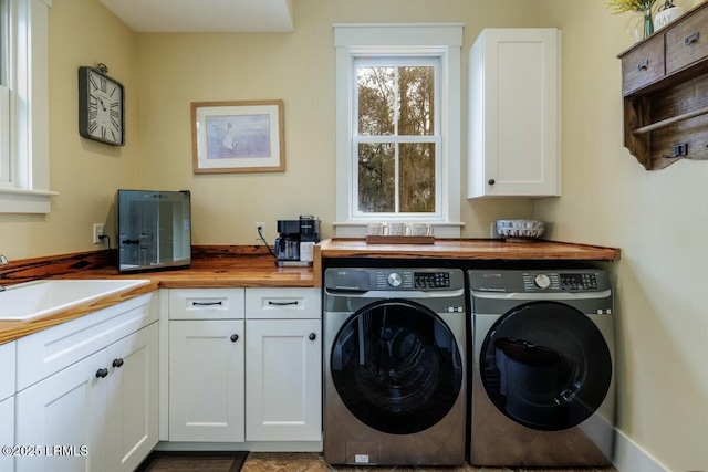 washroom with washer and clothes dryer, a sink, and cabinet space