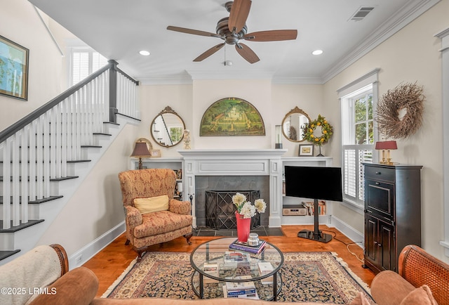 living room with crown molding, a fireplace with flush hearth, wood finished floors, and visible vents