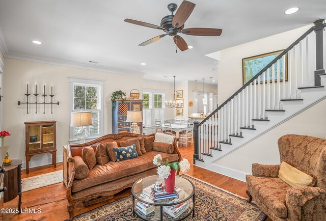 living room with baseboards, wood finished floors, stairs, and ornamental molding