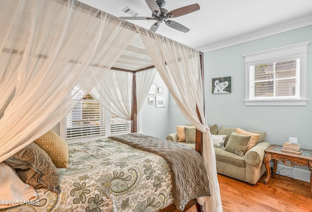 bedroom with visible vents, wood finished floors, a ceiling fan, and ornamental molding