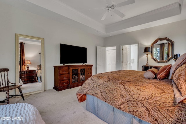 carpeted bedroom with ceiling fan, ornamental molding, and a tray ceiling