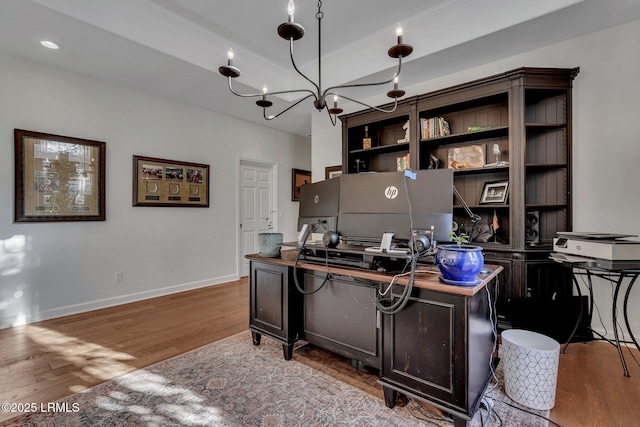 office area featuring crown molding, a chandelier, a raised ceiling, and light wood-type flooring